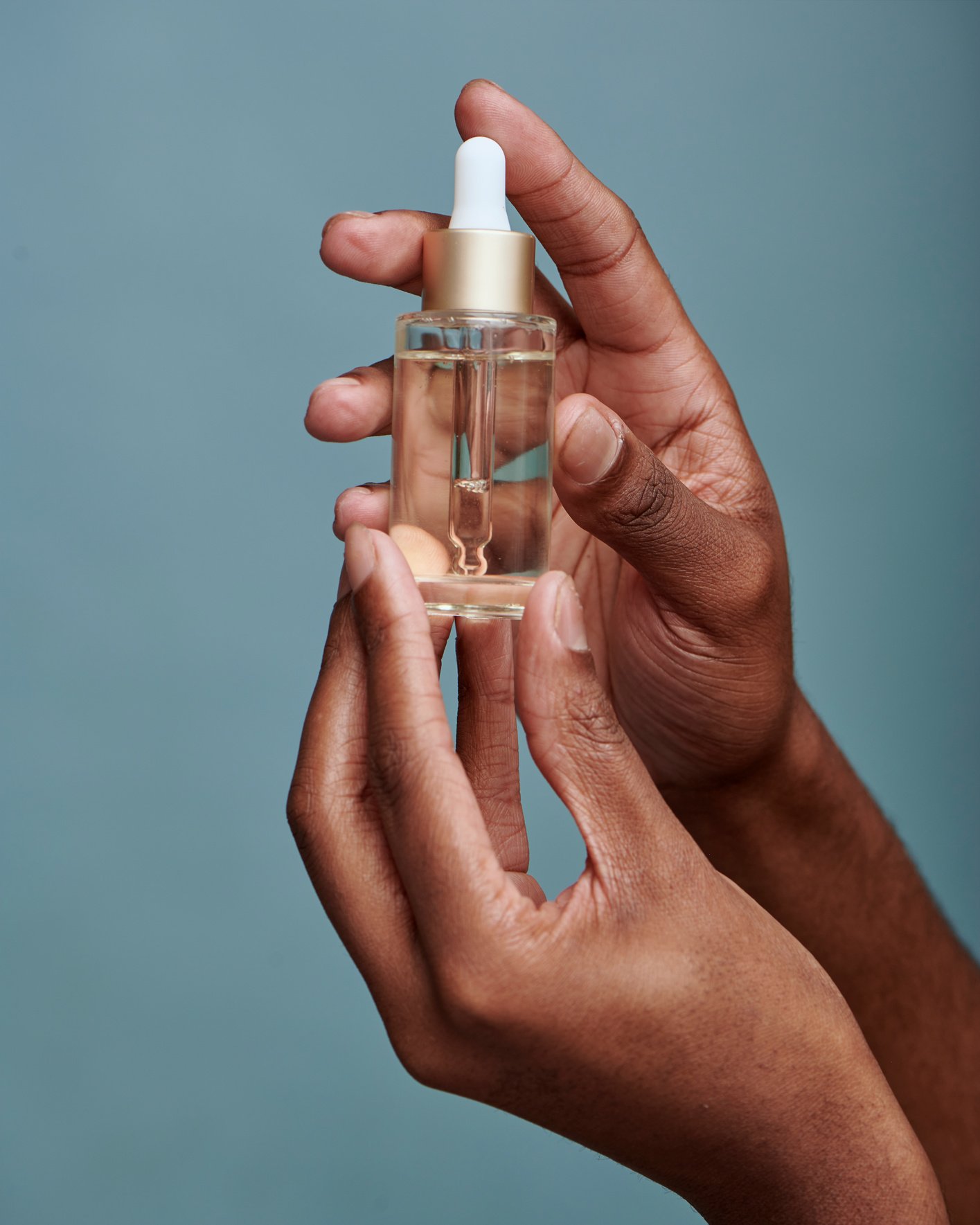 Hands Holding Bottle of Serum